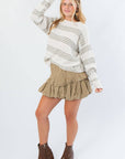 Paige Olive Stripe Textured Sweater styled for autumn with a khaki ruffle skirt and boots, showcasing its relaxed fit and soft knit texture.
