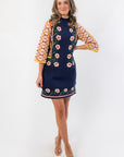 Elegant Penny Lane Navy Jacquard Sweater Dress featuring colorful jacquard sleeves and a flattering short silhouette for casual autumn wear.