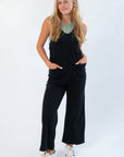 Z Supply True Black Everyday Jersey Jumpsuit with scoop neck, wide straps, and relaxed fit, styled with sneakers for casual comfort.
