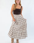 Model wearing basic brown sleeveless bodysuit with scoop neckline, paired with boots and plaid skirt for a cozy fall look.