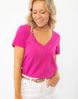 Z Supply Magenta Asher V-Neck Tee with a relaxed fit, short sleeves, and curved hemline, styled with white jeans for a casual look.