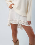 Free People Sugar Swizzle Midnight Muse Half Slip with romantic crochet trim in ivory, styled with a cozy sweater and boots for layered fall fashion.