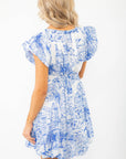 Back view of the Meet Me in Santorini Dress highlighting the elastic waist and flowy silhouette in a blue and white resort print.