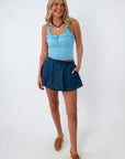 woman smiling in blue ruffle tank top and denim skirt