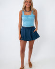 Woman wearing denim skort with side pockets and ruffled top