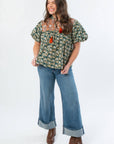 Model wearing THML Green Floral Color Block Puff Sleeve Top paired with wide-leg cuffed jeans and boots, ideal for fall fashion.