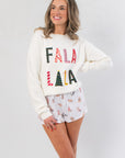 Fa La La White Festive Sweater – Cozy Holiday Knit with colorful holiday lettering, styled with printed sleep shorts for a cheerful winter look.