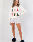 Front view of Fa La La White Festive Sweater – Cozy Holiday Knit, paired with holiday-themed shorts and slippers, perfect for lounging in style.