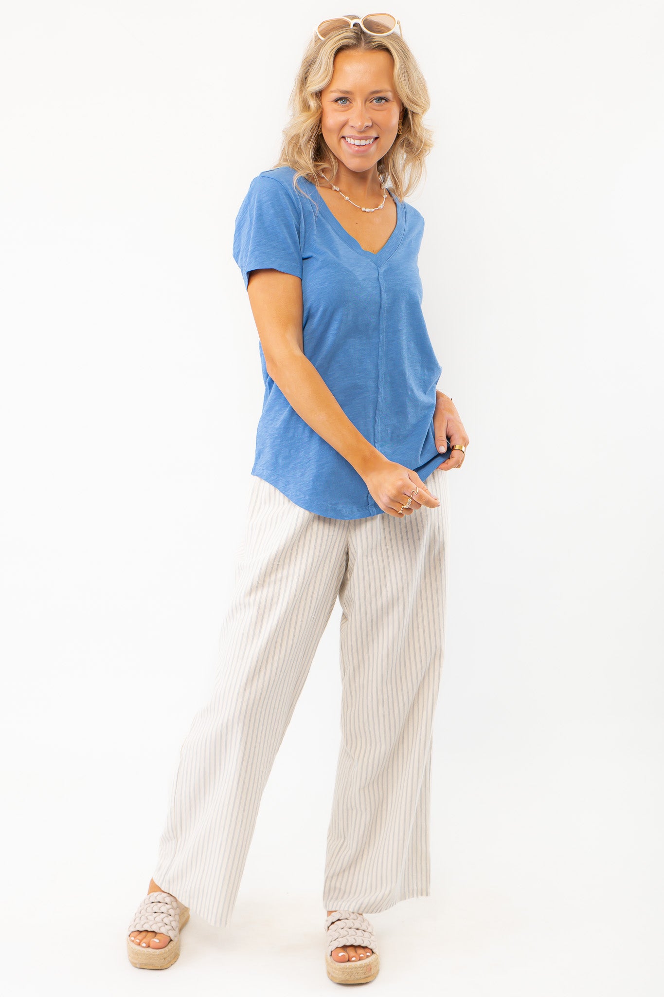Z Supply Asher V-Neck Tee in Riviera Blue styled with neutral striped pants and platform sandals, ideal for a relaxed weekend outfit.