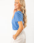 Side view of Z Supply Asher Riviera Blue V-Neck Tee highlighting soft cotton texture and flattering curved hem, styled with striped pants.