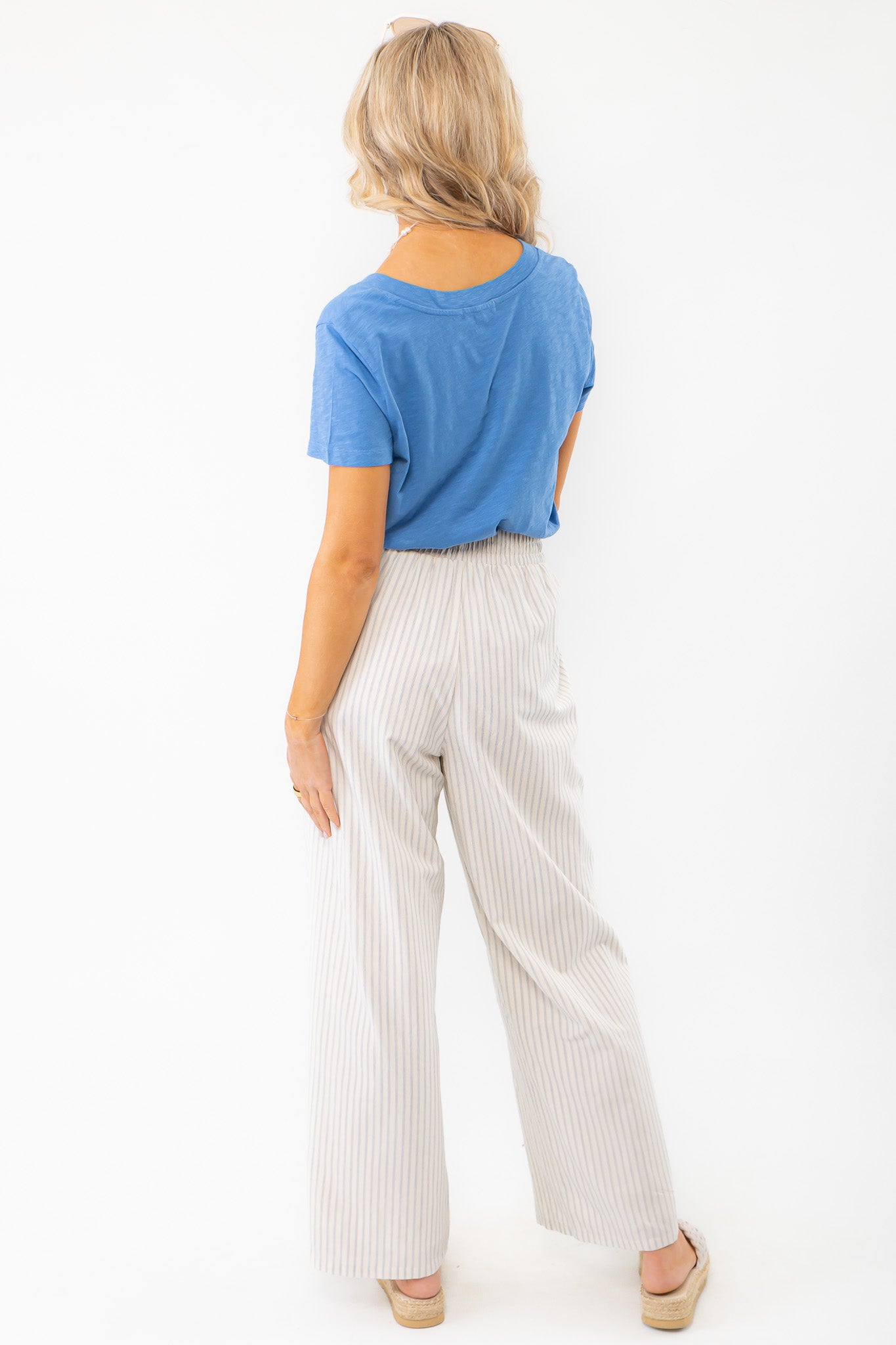 Back view of Z Supply Asher Riviera Blue V-Neck Tee showing relaxed fit and lightweight cotton slub jersey fabric paired with striped pants.
