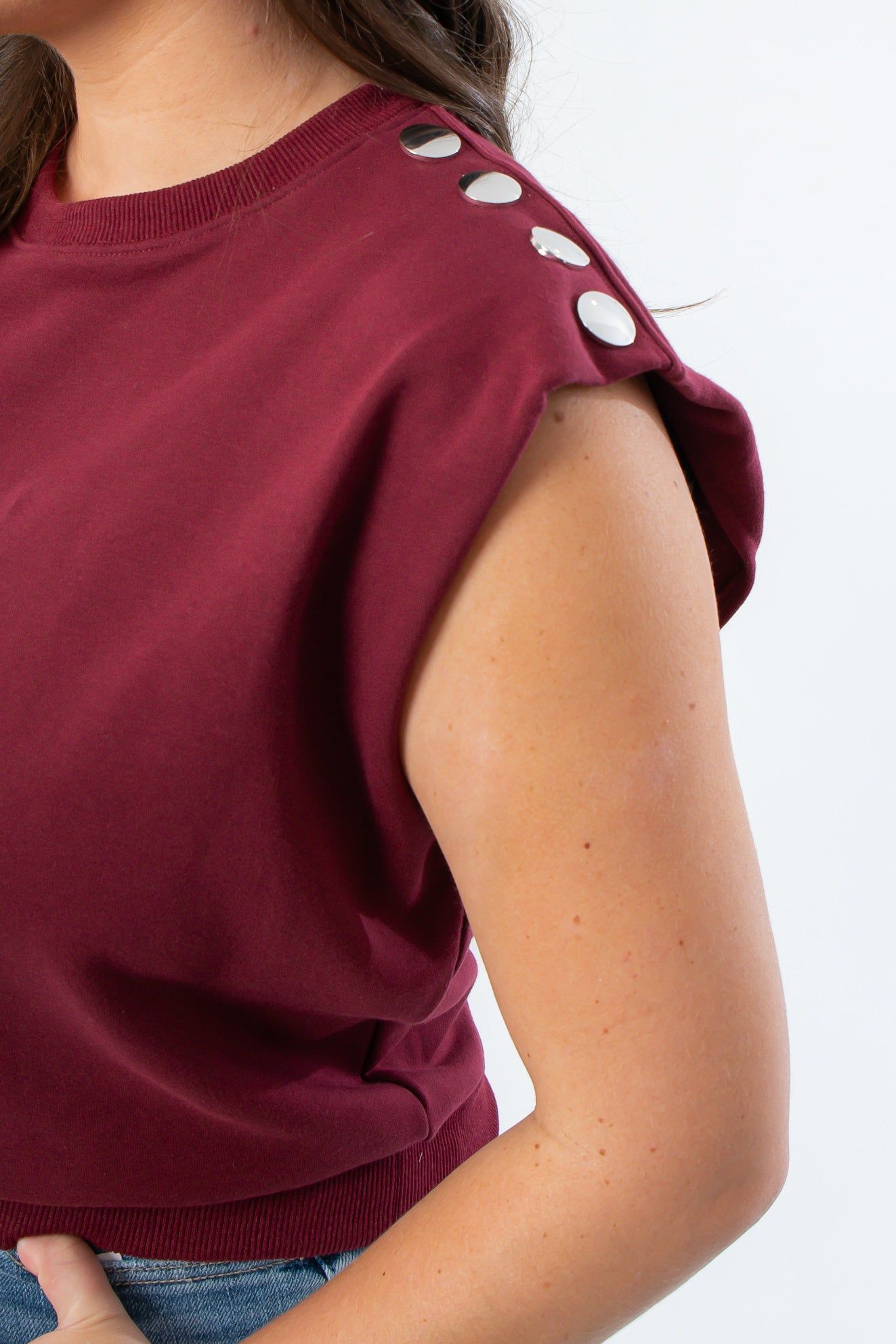 Close-up of THML Burgundy Studded Sleeveless Top showing silver stud details on thick sweatshirt fabric.