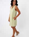 Back view of woman in yellow embroidered sundress with shell necklace
