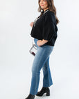 Side view of Angie Black V-Neck Polo Sweater showing relaxed fit and cropped hem, styled with denim and ankle boots.