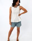 Side view of woman in white peplum blouse with colorful beaded necklace, smiling