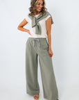 Women wearing sage green wide-leg lounge pants with matching sweatshirt tied around shoulders