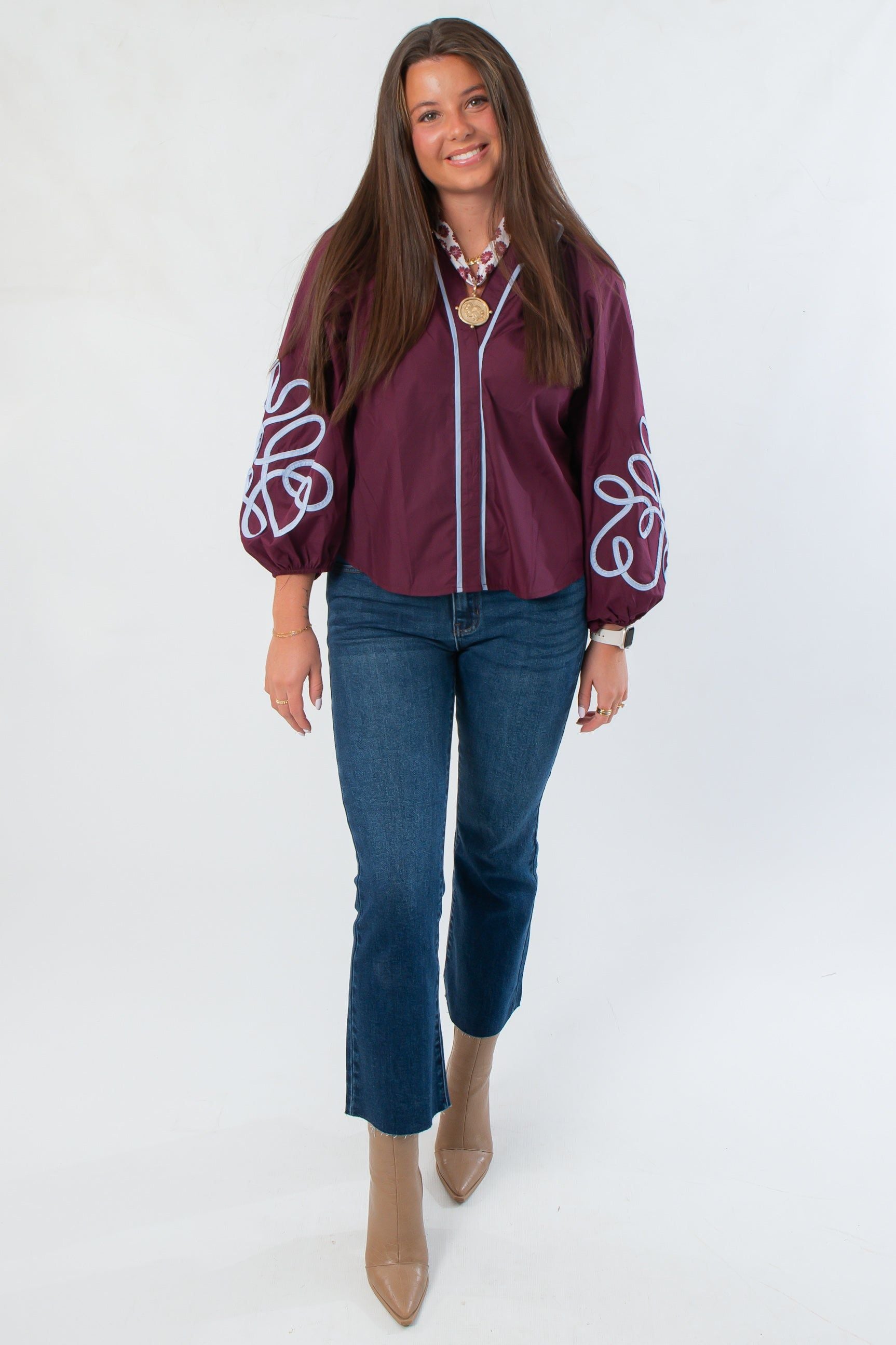 Glam Wine Long Sleeve Blouse with white embroidery on balloon sleeves, styled with blue jeans and tan ankle boots for a chic fall look.