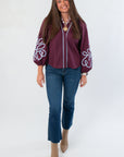 Glam Wine Long Sleeve Blouse with white embroidery on balloon sleeves, styled with blue jeans and tan ankle boots for a chic fall look.
