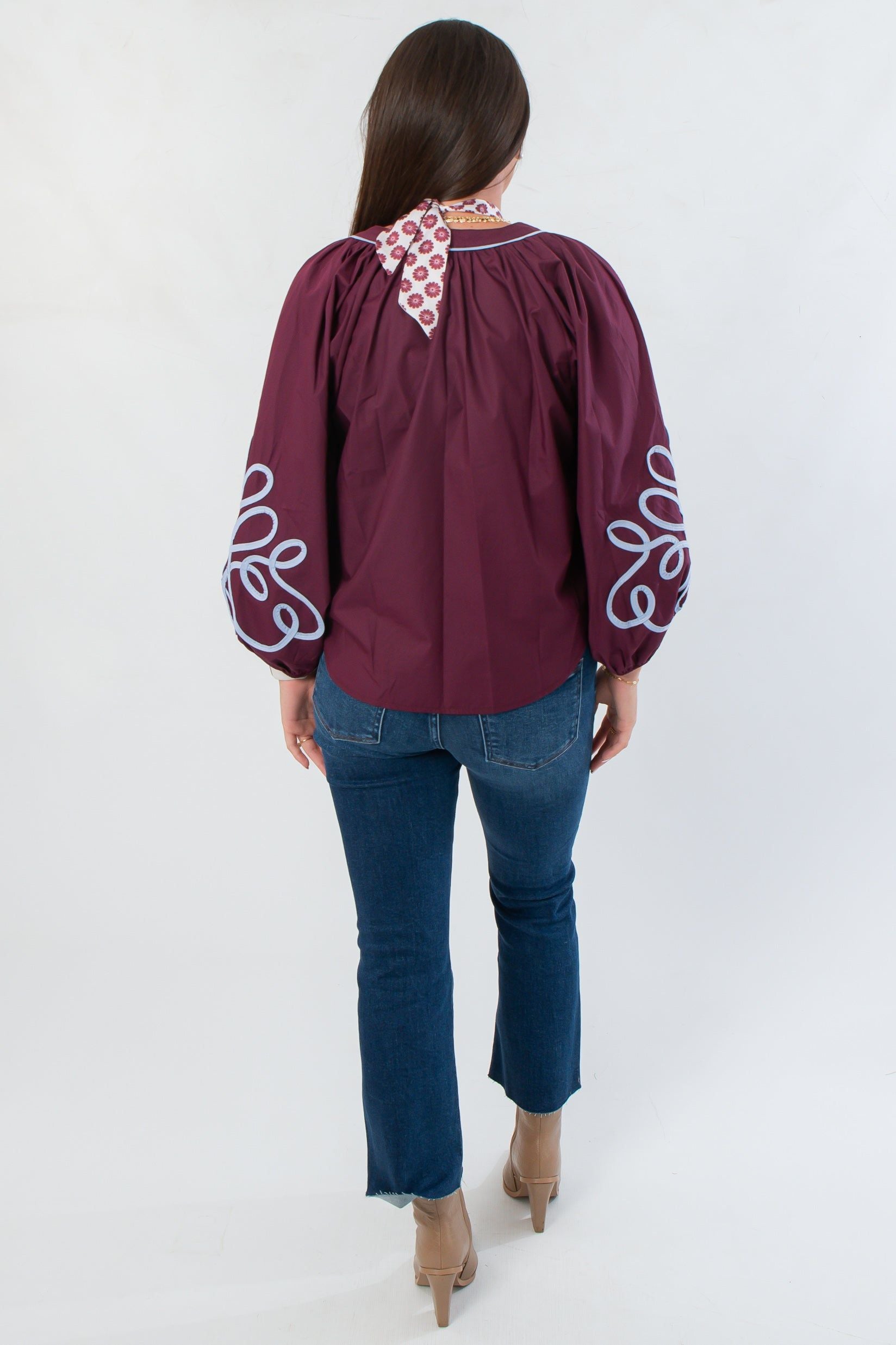 Back view of Wine Multi Long Sleeve Embroidered Blouse with gathered shoulders and flowy silhouette, paired with cropped jeans and boots.