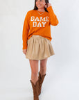 Oversized Game Day Orange Knit Sweater paired with a tan skirt and brown boots, perfect for autumn football weekends.
