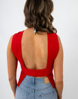 Woman in red sleeveless knit top with open back at go-kart track