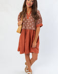 Rust embroidered babydoll dress featuring a flowy skirt and V-neckline, ideal for fall fashion or Thanksgiving events.