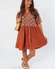 Chateau Chic Rust Embroidered Babydoll Dress with flared silhouette and textured top, perfect for casual autumn outings.