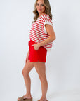 Woman wearing a red and white striped shirt and red shorts on a white background
