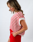 Woman wearing a red and white striped sleeveless top with red shorts on a white background