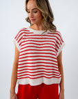 Woman wearing a red and white striped sleeveless top with red shorts on a white background