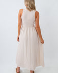 Woman wearing a beige sleeveless dress on a white background