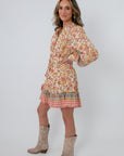 Back view of Clyvedon Cream Floral Patterned Mini Dress with floral print and border hem, styled with beige cowboy boots