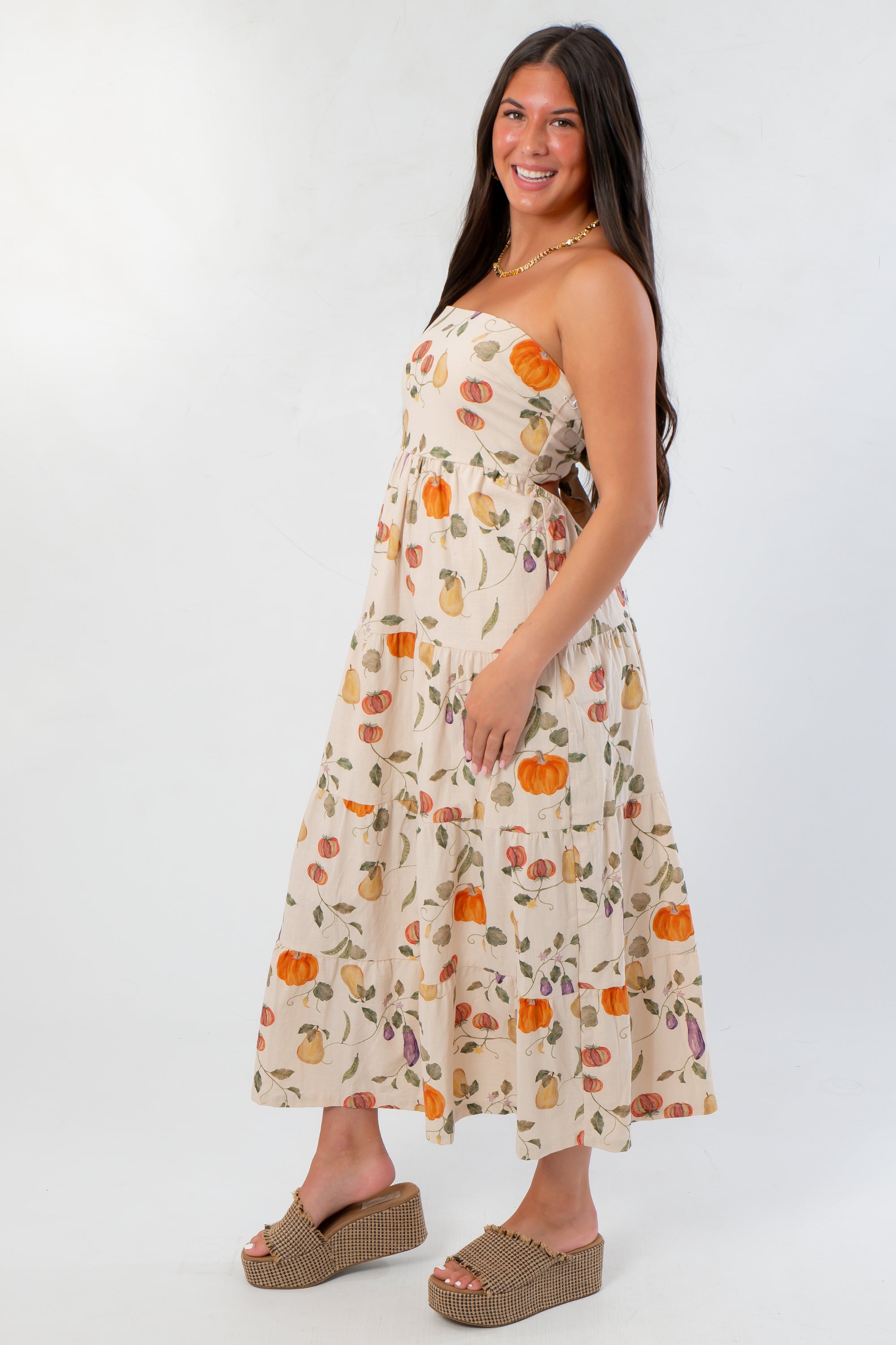 Side profile of Heirloom Pumpkin Harvest Strapless Midi Dress showing flowy fit and colorful harvest pattern, great for casual autumn wear.