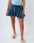 Person wearing a blue denim skirt and light blue top on a white background