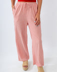 Person wearing pink striped pants and a red top on a white background