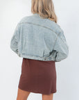 Back view of Maci Medium Wash Crop Denim Jacket – Classic & Trendy, highlighting adjustable waist tabs and faded denim texture.