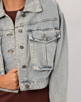 Close-up of Maci Medium Wash Crop Denim Jacket – Classic & Trendy, featuring distressed flap pockets and metal button detailing.