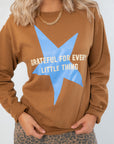 Close-up of Grateful for Everything Graphic Star Sweatshirt showing blue star graphic and white text on soft brown fabric. Ideal for cozy fall looks.