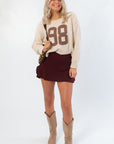 Dark Cherry Yoga Skort with crossover waistband and built-in shorts, styled with a beige sweater and cowboy boots for casual fall wear.