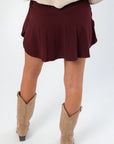 Back view of Dark Cherry Cross Over Yoga Skort highlighting flowy design and built-in shorts, perfect for movement and comfort.