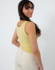 Model wearing yellow summer tank top with cream pants