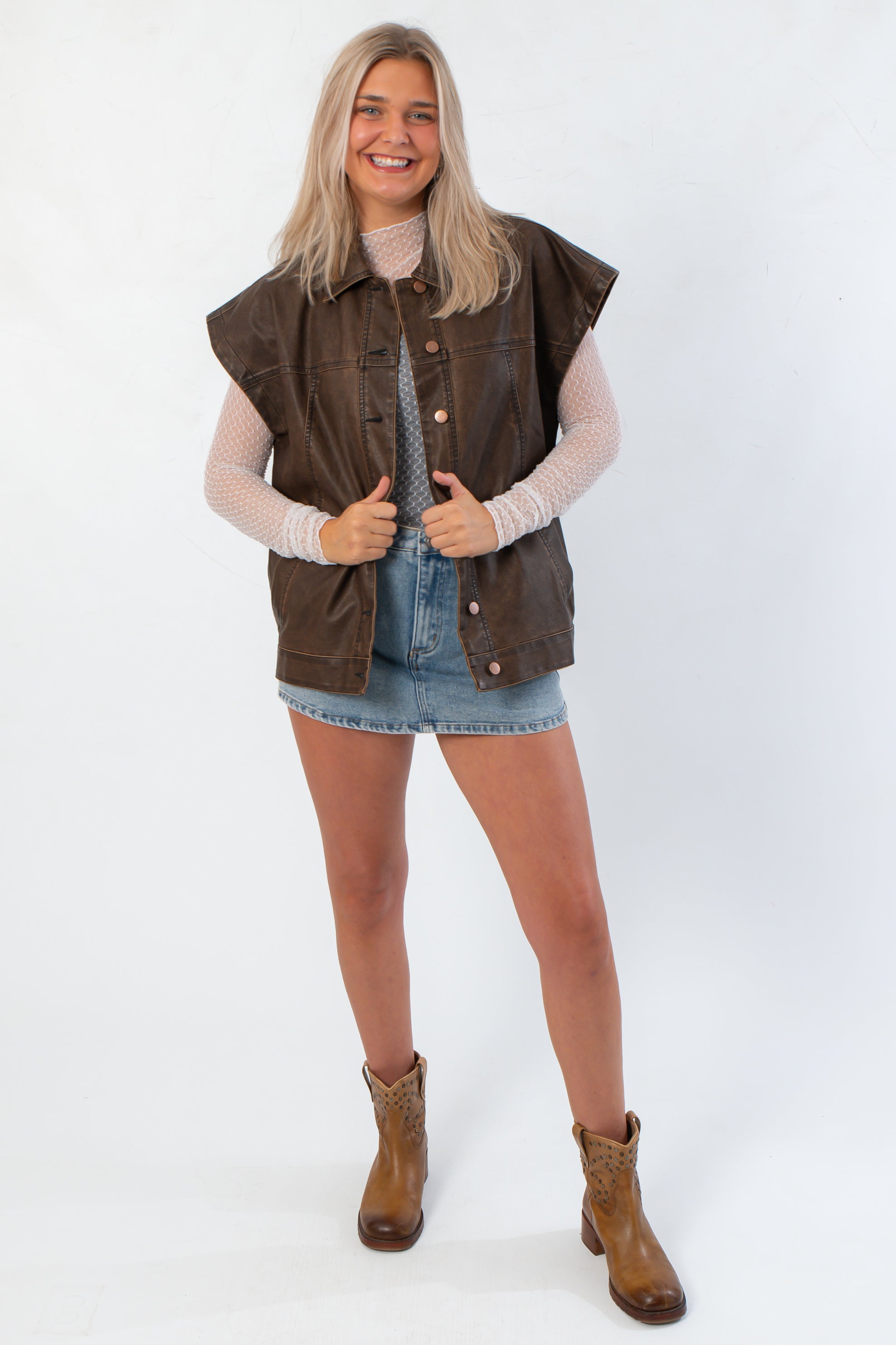 Model wearing Bittersweet Chocolate Brown Faux Leather Oversized Vest – Modern Style with casual boots and denim skirt, ideal for streetwear layering.
