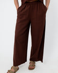 Close-up of women in brown linen pants with elastic waistband, showing relaxed fit and fabric texture