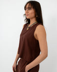 Back view of brown linen tank top with button closure at neckline, styled with jewelry and matching linen pants