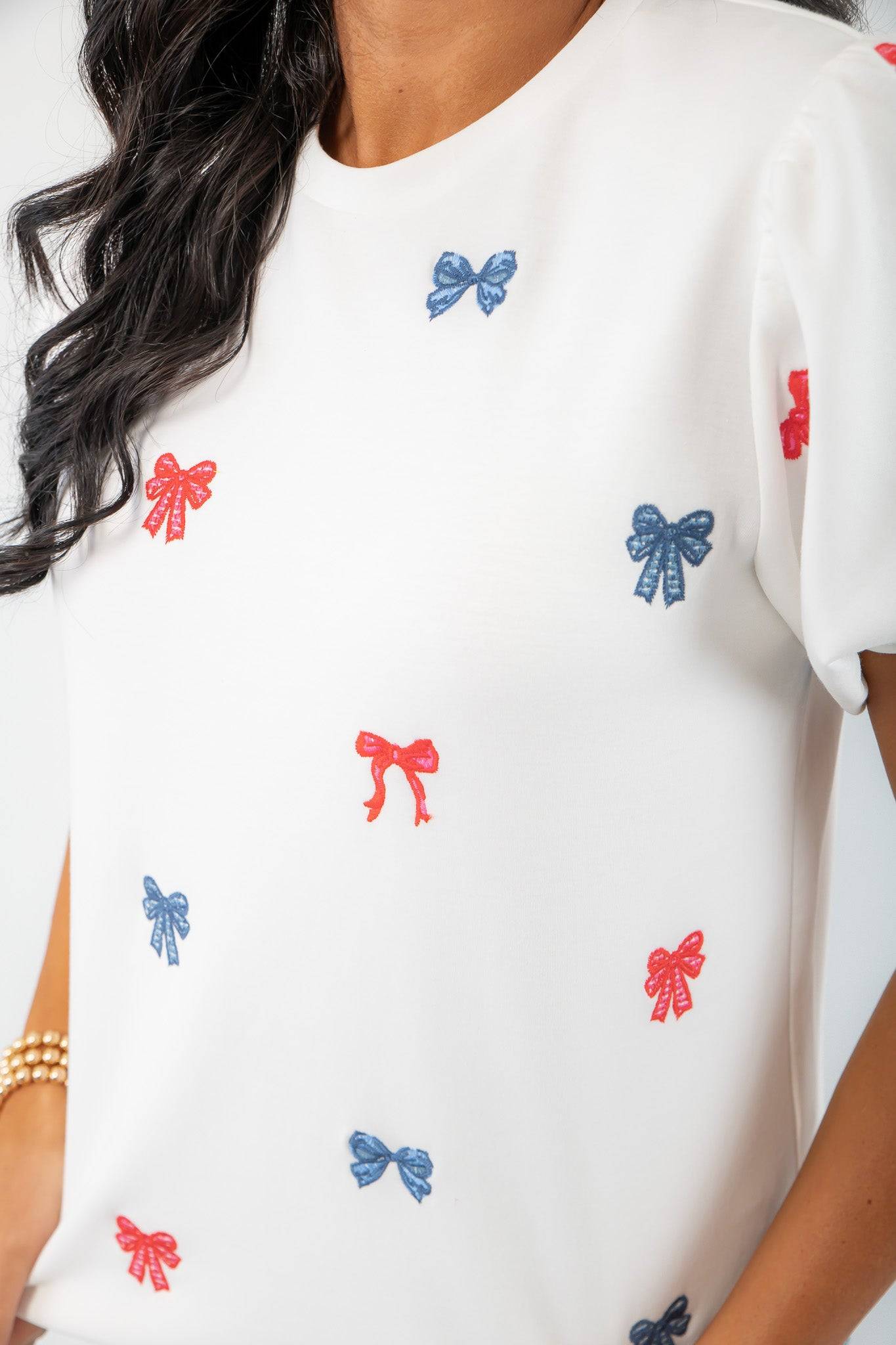 Close-up of THML Red & Blue Bow Embroidery Top showing detailed red and blue bow embroidery on soft white fabric for a chic patriotic look.