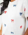 Close-up of THML Red & Blue Bow Embroidery Top showing detailed red and blue bow embroidery on soft white fabric for a chic patriotic look.