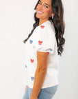 Side profile of THML Red & Blue Bow Embroidery Top with puff sleeves and embroidered bows, perfect for festive summer occasions.