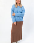 Cozy and stylish Lorelai Blue Marbled Round Neck Sweater featuring side slits and relaxed fit, paired with a long brown skirt and boots.