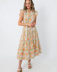 Model in a floral midi dress with ruffled sleeves and a tie waist, showcasing a spring floral pattern