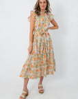 Model wearing floral midi dress with waist tie and ruffled shoulder details